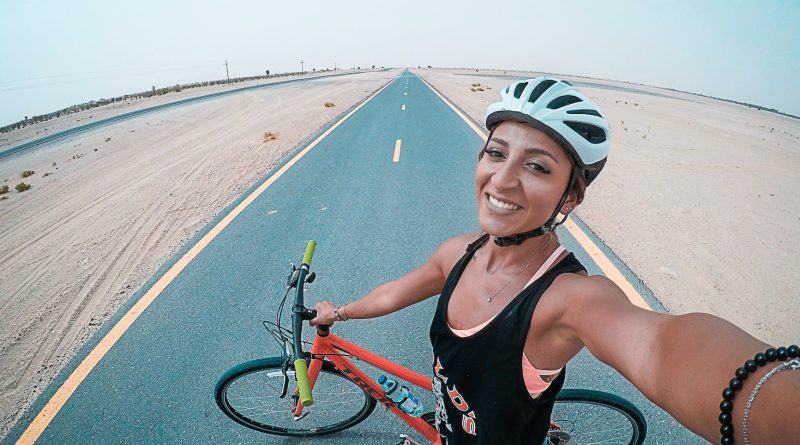 woman holding bicycle on asphalt road